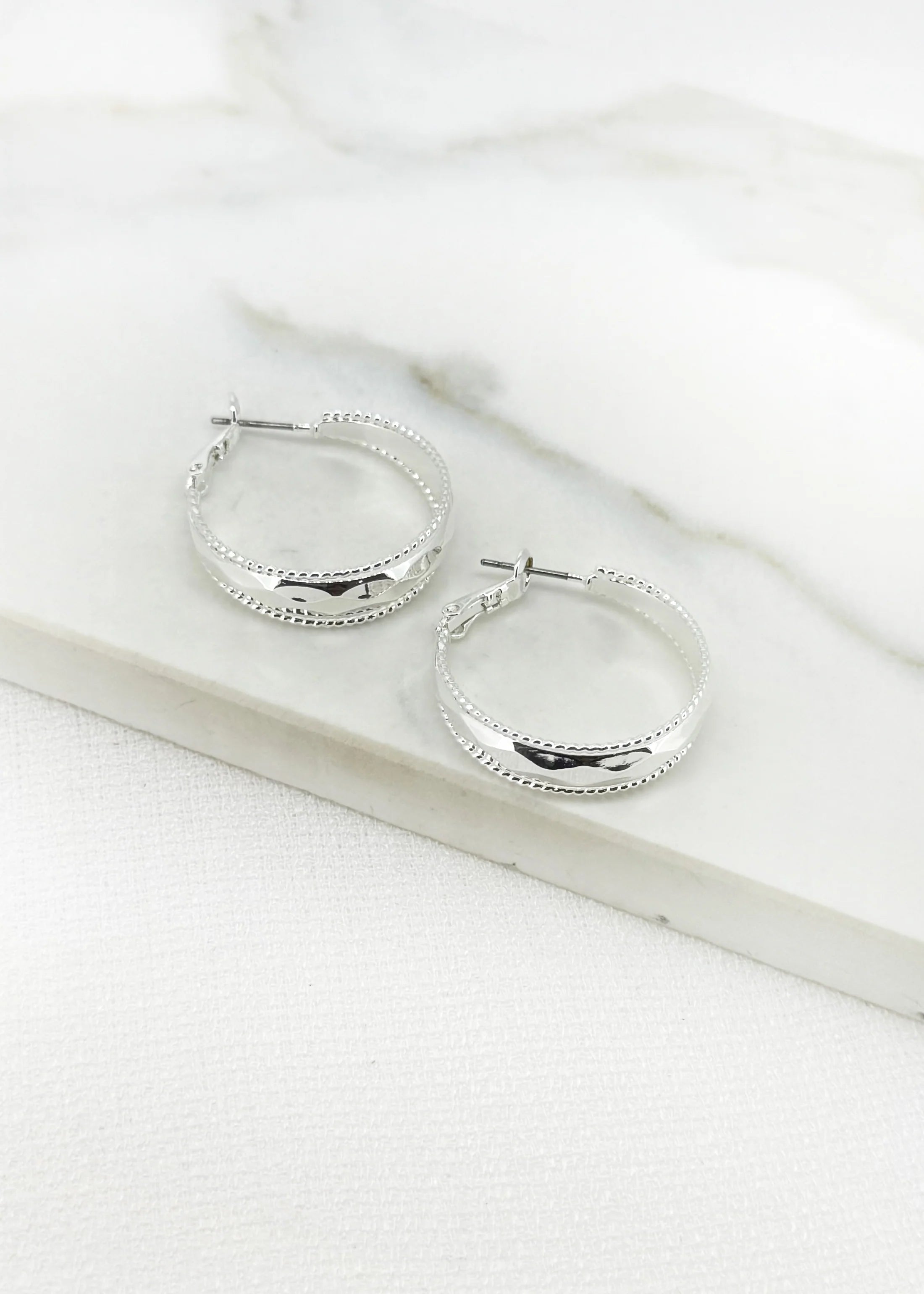 Silver hoop earring with faceted detail